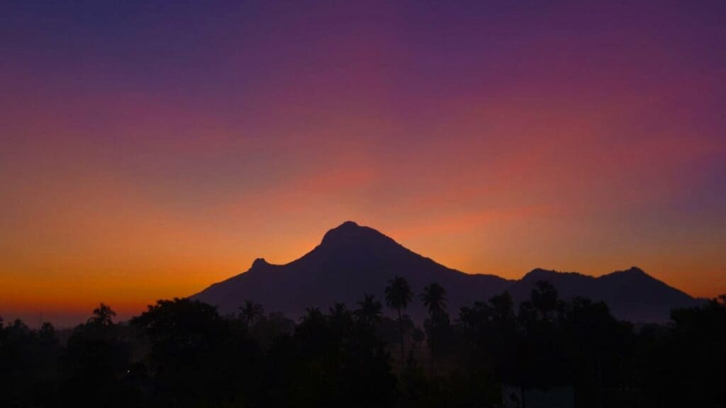 A mountain range with the sun setting in the background.