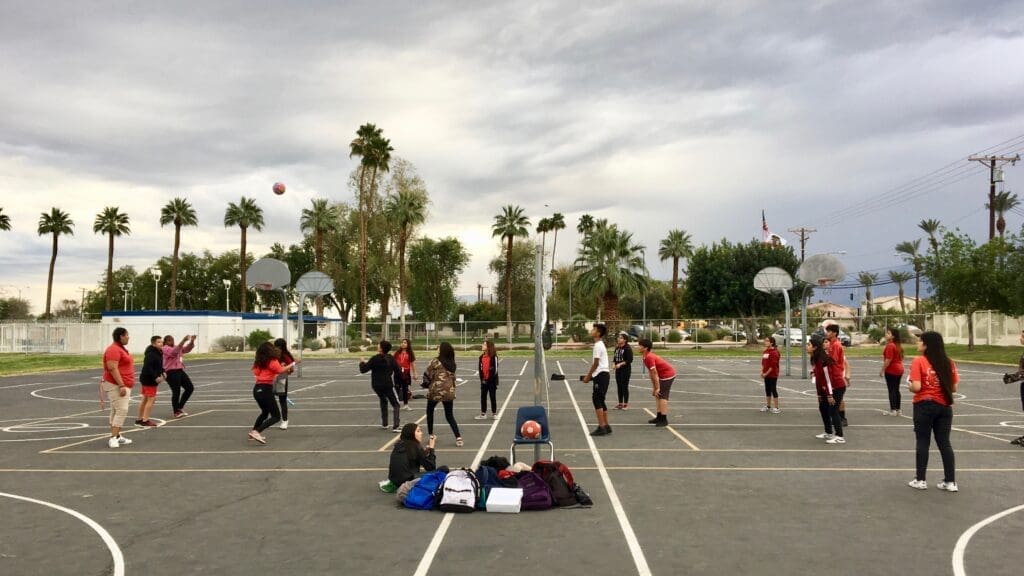 A group of people playing volleyball in an empty parking lot.