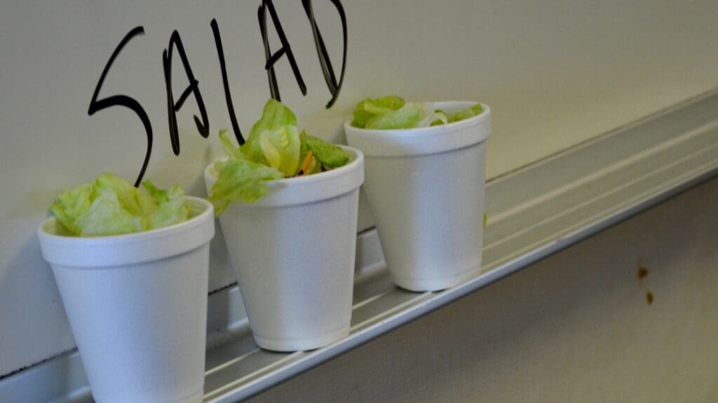 Three white cups with salad in them on a counter.