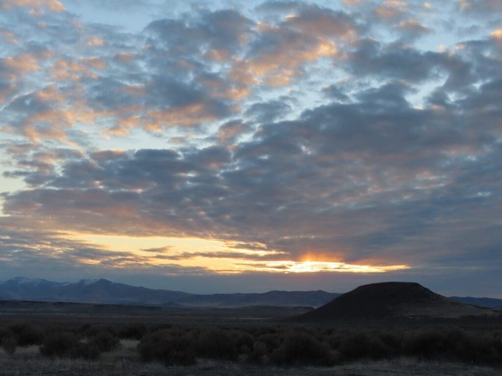 A sunset with clouds in the sky over a desert.