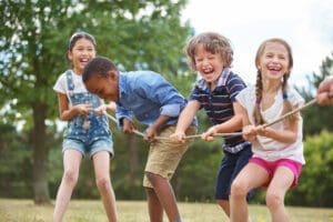 A group of kids playing tug-o-war with ropes.