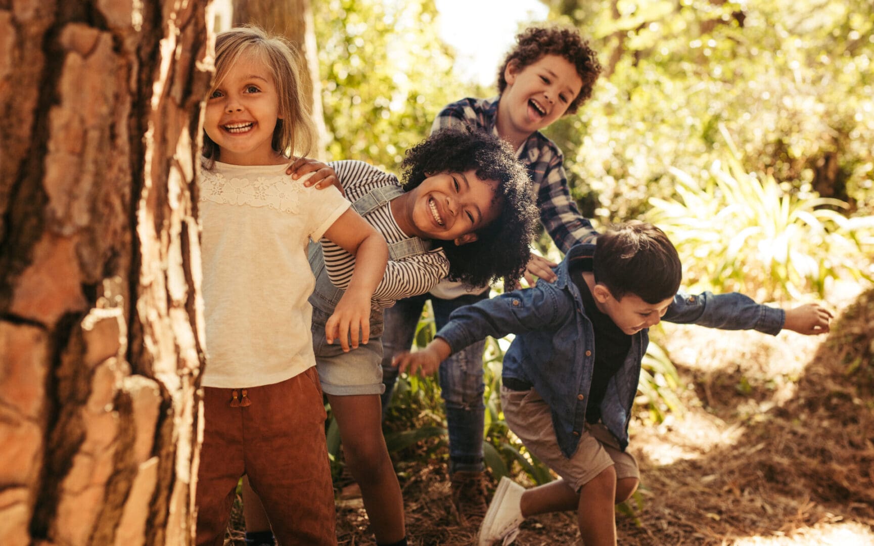 Cute,Smiling,Kids,Peeking,Out,From,Behind,The,Tree,In