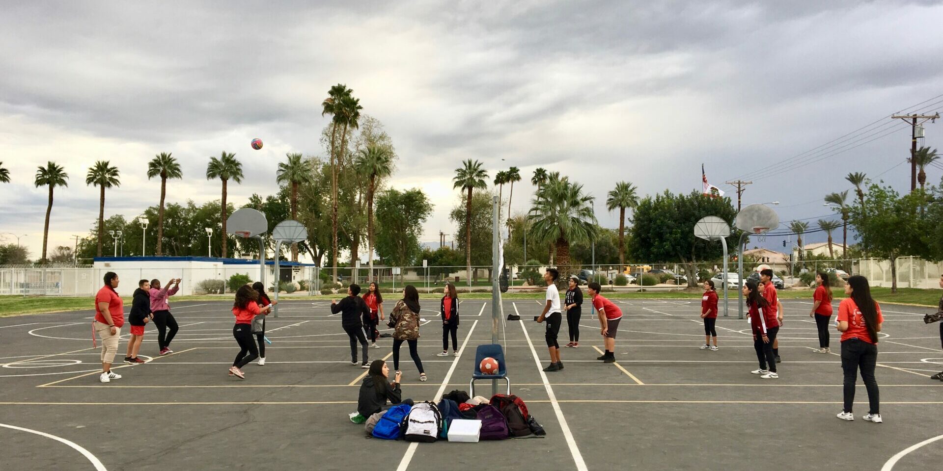 A group of people playing volleyball in an empty parking lot.