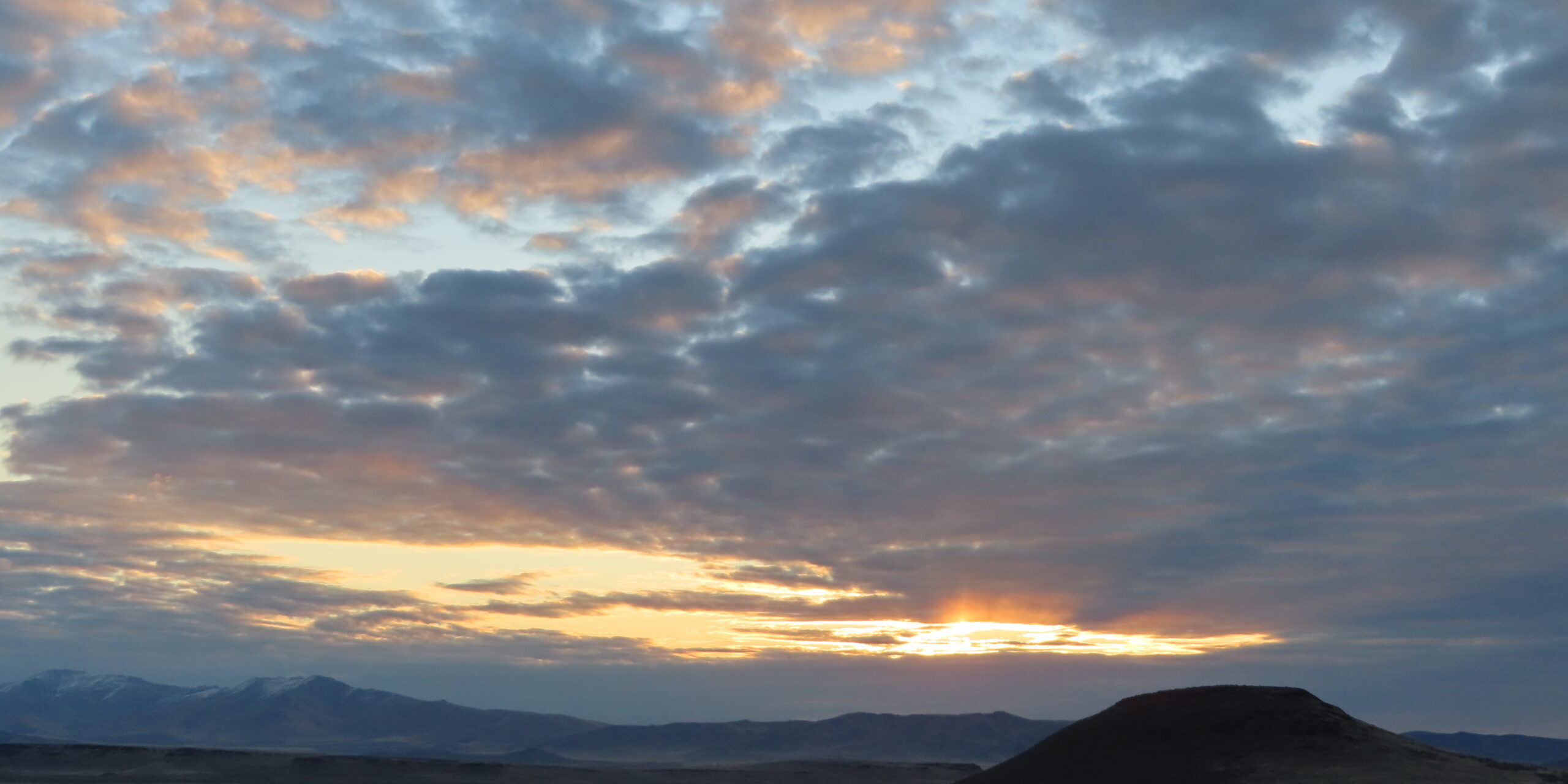 A sunset with clouds in the sky over a desert.